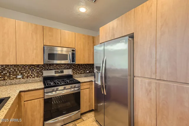 a kitchen with stainless steel appliances granite countertop a stove a sink and a refrigerator