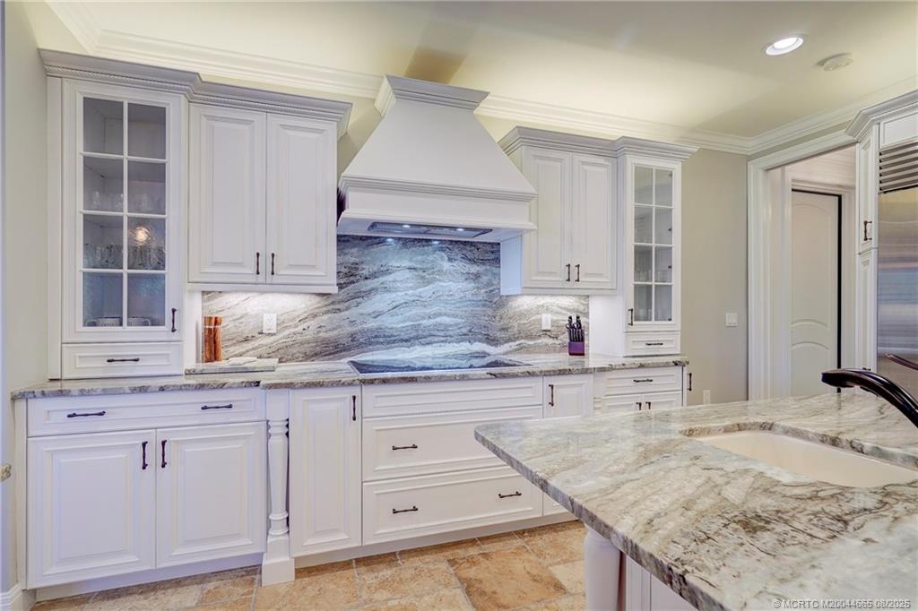 1528 Northeast Outrigger Landings Drive, Unit 208 Jensen Beach, FL 34957 - Photo 31 of 79 a kitchen with granite countertop a sink and white cabinets