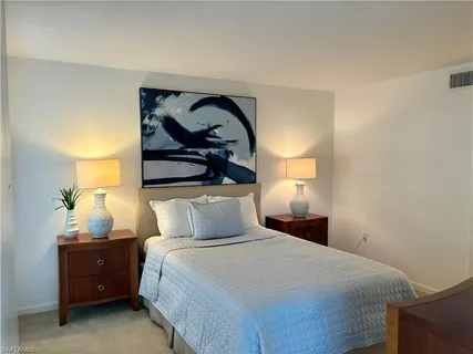 a bedroom with a bed and lamp on dresser