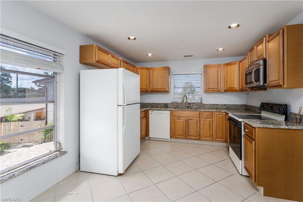 180 Cypress Way East, Unit B212 Naples, FL 34110 - Photo 11 of 40 a kitchen with stainless steel appliances granite countertop a refrigerator sink and cabinets