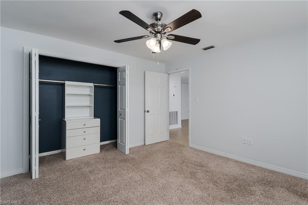 180 Cypress Way East, Unit B212 Naples, FL 34110 - Photo 19 of 40 a view of an empty room with closet and a ceiling fan