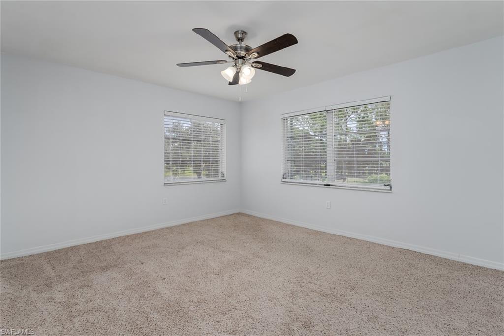 180 Cypress Way East, Unit B212 Naples, FL 34110 - Photo 22 of 40 an empty room with ceiling fan and windows