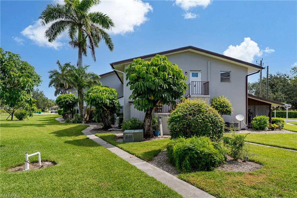 180 Cypress Way East, Unit B212 Naples, FL 34110 - Photo 38 of 40 a view of a house with a yard and potted plants