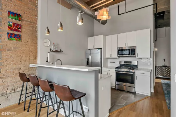 a kitchen with stainless steel appliances a stove a refrigerator and a dining table with wooden floor