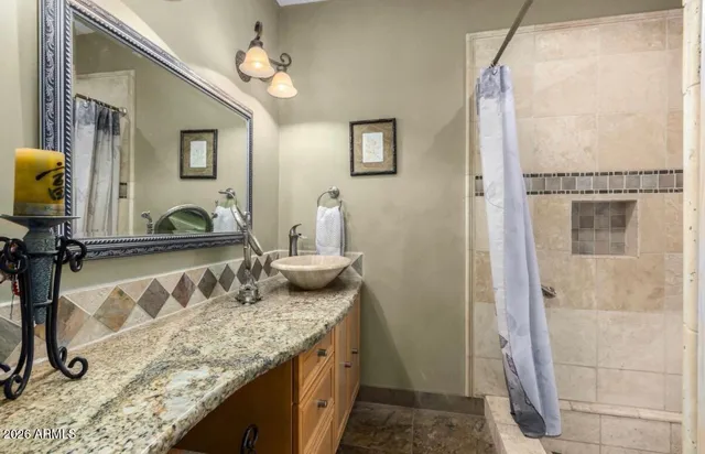a bathroom with a granite countertop sink a mirror and shower