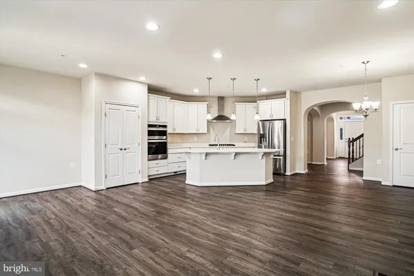 an open kitchen with white cabinets stainless steel appliances and wooden floor