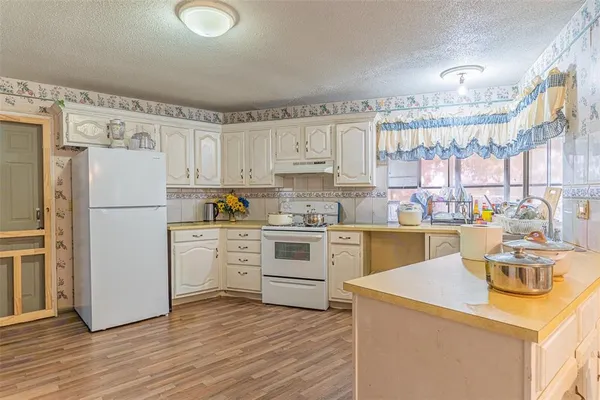 a kitchen with a refrigerator a stove a sink and white cabinets with wooden floor