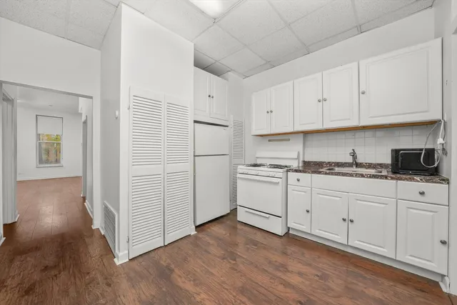 a kitchen with granite countertop white cabinets and white appliances