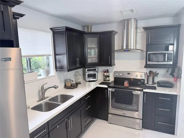 a kitchen with stainless steel appliances granite countertop a sink stove and microwave