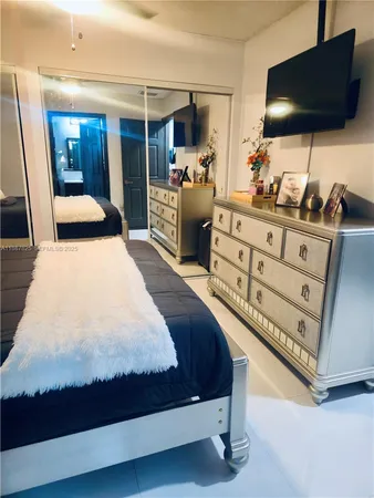 a bedroom with a bed and a flat tv screen on dresser