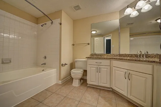 a spacious bathroom with a granite countertop sink a toilet mirror and shower