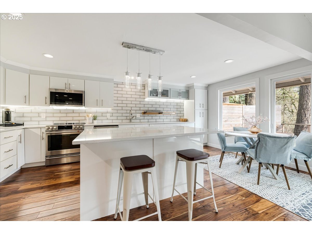4268 Woodside Circle Lake Oswego, OR 97035 - Photo 5 of 44 a kitchen with stainless steel appliances kitchen island granite countertop a stove a sink a dining table and chairs