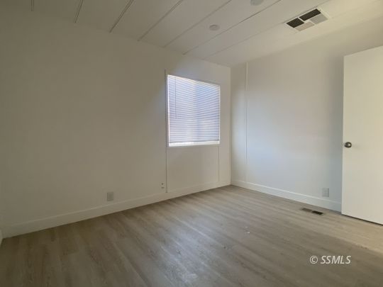 821 West Bennett Street Ridgecrest, CA 93555 - Photo 13 of 26 an empty room with wooden floor and windows