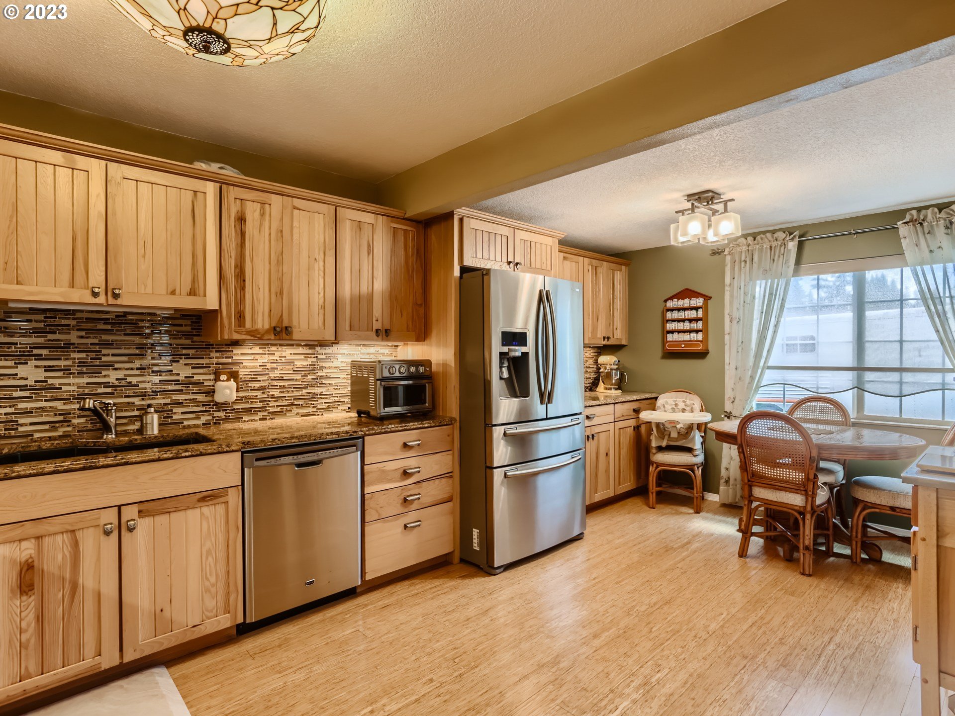 13611 South Union Hall Road Canby, OR 97013 - Photo 11 of 29 a kitchen with stainless steel appliances granite countertop a refrigerator a sink dishwasher a dining table and chairs with wooden floor