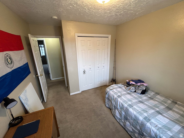 939 South Freedom Boulevard, Unit 13 Provo, UT 84601 - Photo 13 of 26 Bedroom featuring carpet floors, a closet, and a textured ceiling