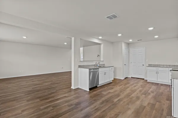 a large kitchen with stainless steel appliances granite countertop a large stove a refrigerator a sink and white cabinets with wooden floor