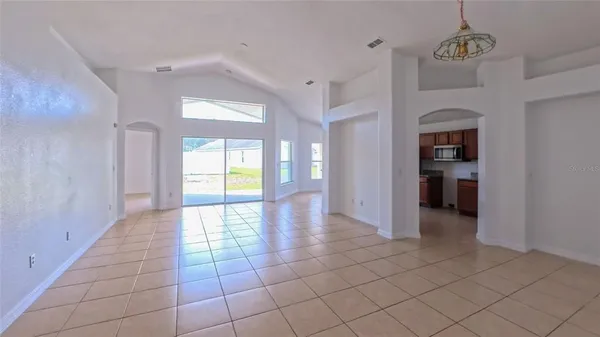 a view of a hallway to an empty room with a window