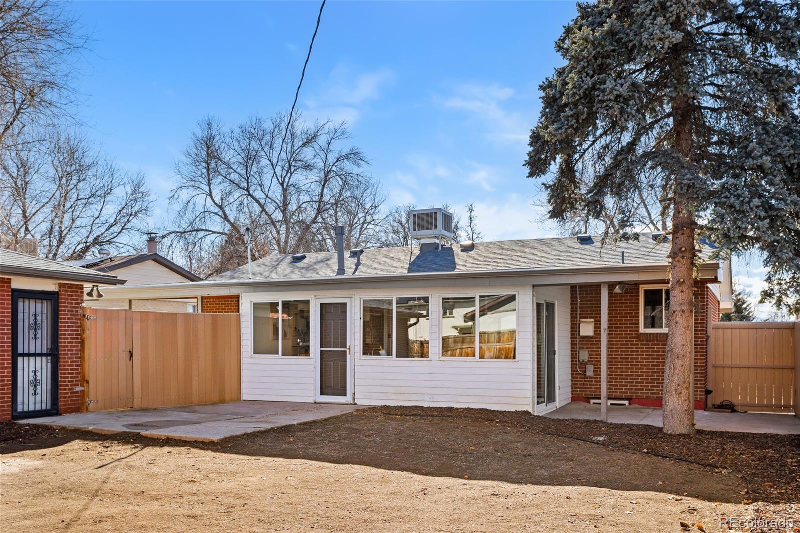 8140 Raleigh Street Westminster, CO 80031 - Photo 36 of 39 a view of a white house with a large tree and wooden fence