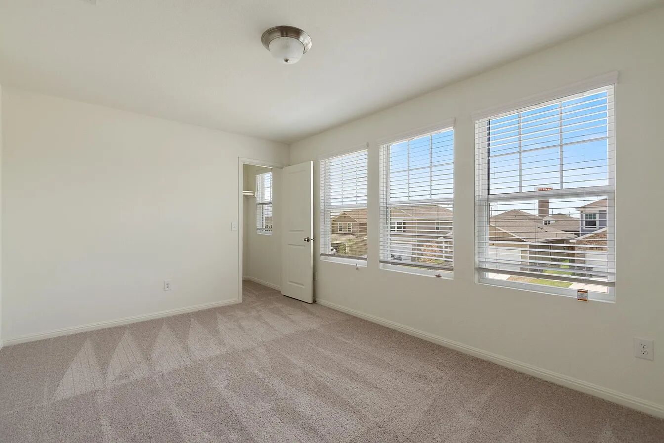 101 Aoudad Road Hutto, TX 78634 - Photo 34 of 39 A well-lit bedroom features plush carpeting and multiple windows for abundant daylight.