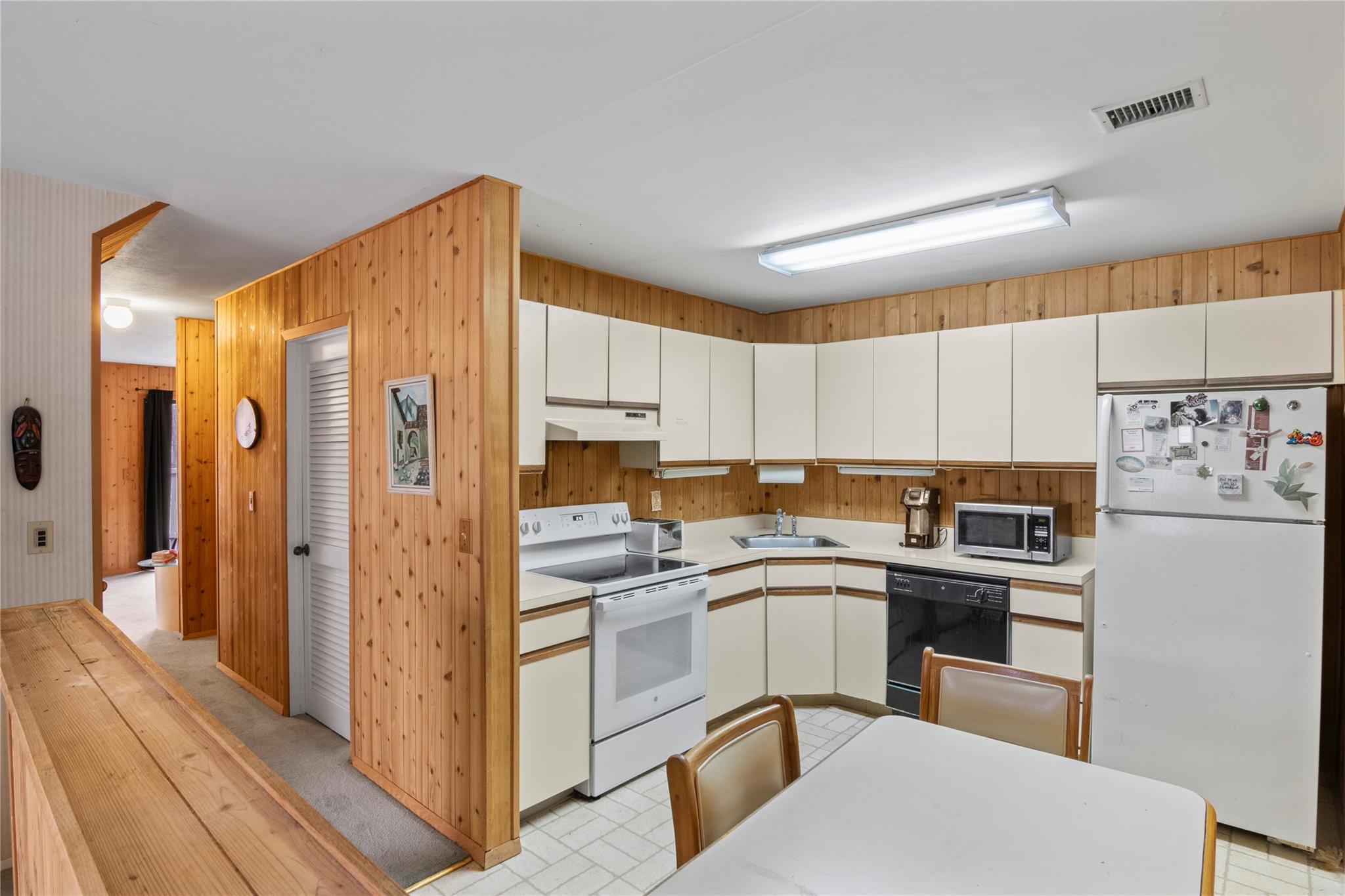 154 Birchwood Road Coram, NY 11727 - Photo 8 of 13 Kitchen featuring visible vents, a sink, under cabinet range hood, white appliances, and light countertops