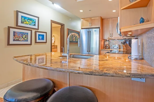 a kitchen with stainless steel appliances granite countertop a sink and a refrigerator