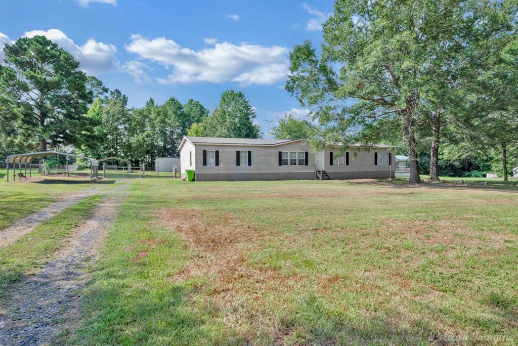 62 Princeton Lane Princeton, LA 71067 - Photo 2 of 33 Manufactured / mobile home with a detached carport, driveway, and view of scattered trees