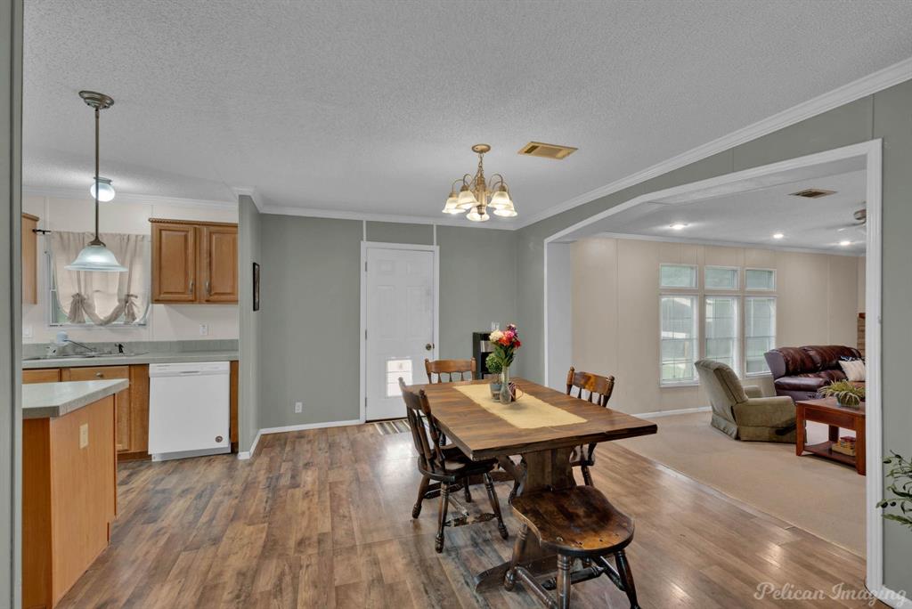 62 Princeton Lane Princeton, LA 71067 - Photo 23 of 33 Dining room with ornamental molding, a textured ceiling, dark wood-style floors, and a chandelier