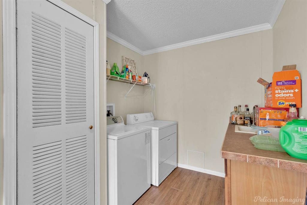 62 Princeton Lane Princeton, LA 71067 - Photo 26 of 33 Washroom with light wood-type flooring, a textured ceiling, crown molding, and washing machine and clothes dryer