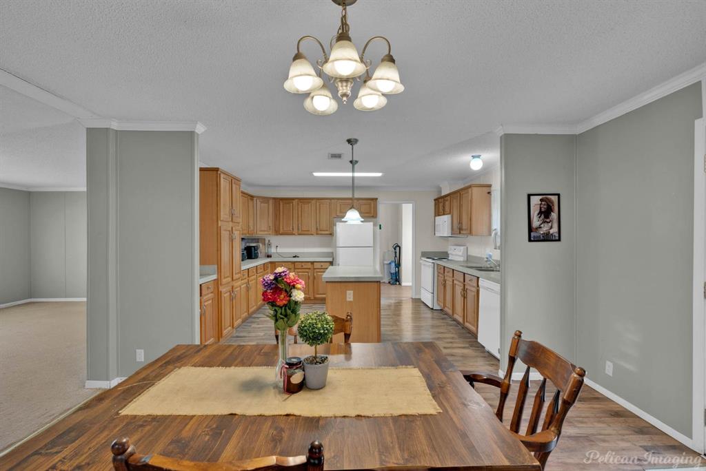 62 Princeton Lane Princeton, LA 71067 - Photo 9 of 33 Dining space with a chandelier, crown molding, a textured ceiling, and light wood-type flooring