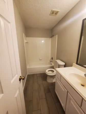 a bathroom with a sink a toilet a mirror and shower