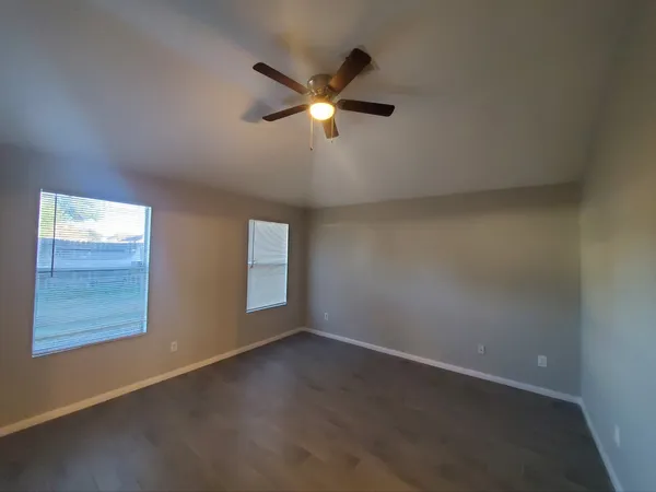 an empty room with windows and fan