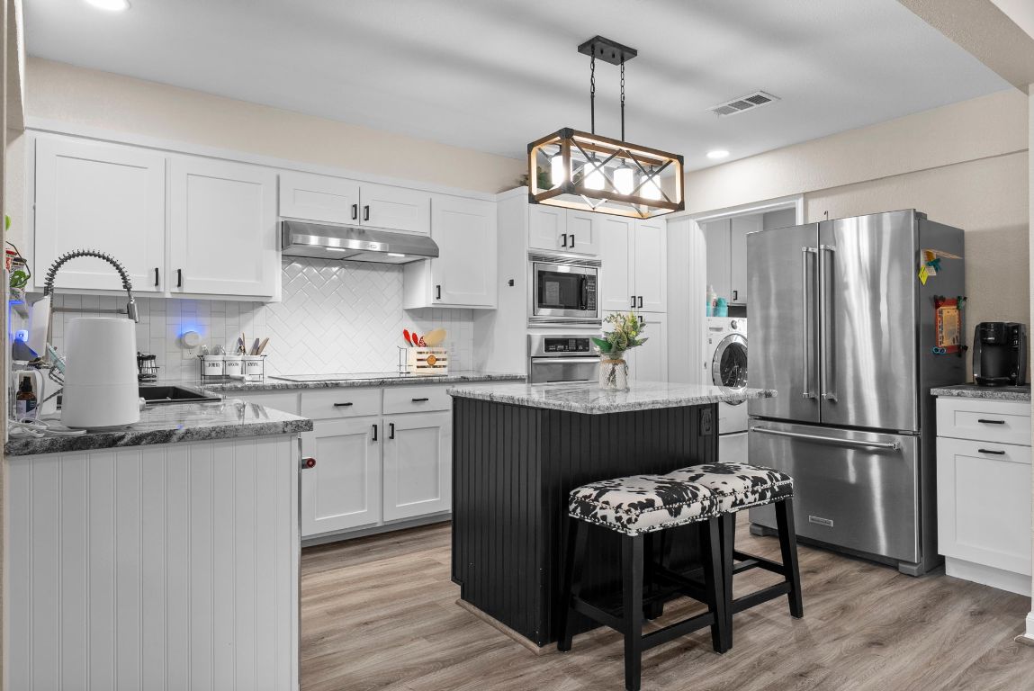 2702 Double Tree Street Round Rock, TX 78681 - Photo 9 of 35 a kitchen with kitchen island granite countertop stainless steel appliances a table and chairs in it