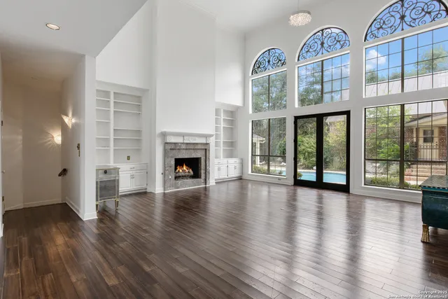 an empty room with wooden floor fireplace and windows