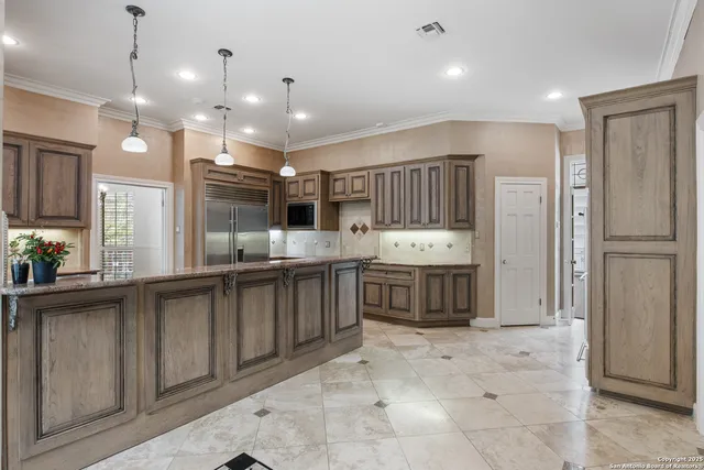 a large kitchen with kitchen island a large counter space stainless steel appliances and cabinets
