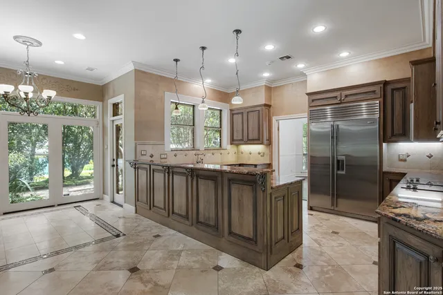 a kitchen with stainless steel appliances kitchen island granite countertop a refrigerator and a sink