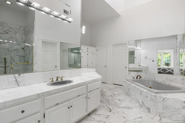 a spacious bathroom with a granite countertop sink a mirror a vanity and shower