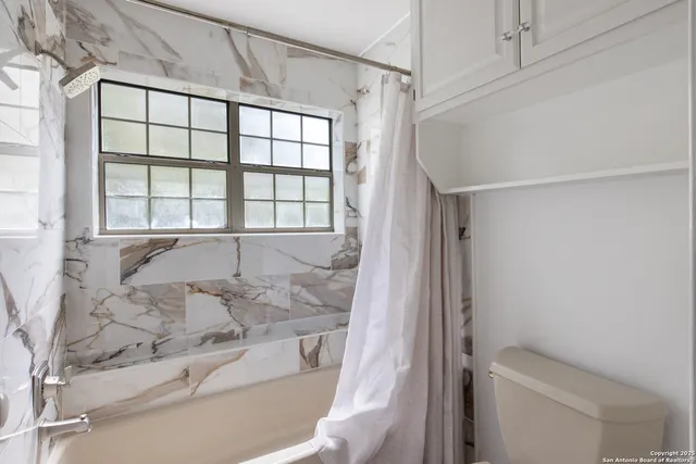 a bathroom with a granite countertop sink a toilet and shower