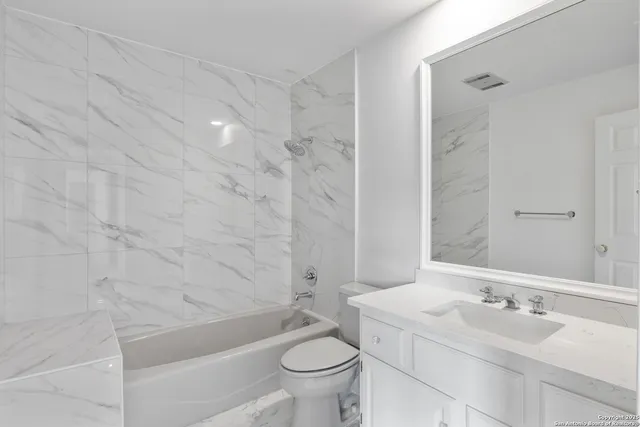 a bathroom with a granite countertop sink a toilet and shower