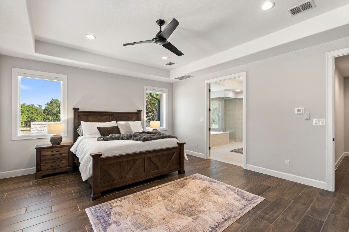 291 Southwick Ranch Road Johnson City, TX 78636 - Photo 17 of 40 Bedroom with a tray ceiling, wood tile floors, ceiling fan, recessed lighting, and ensuite bath