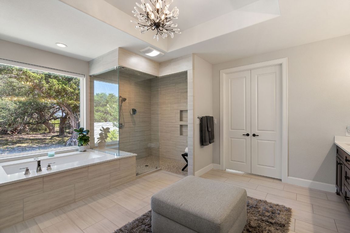 291 Southwick Ranch Road Johnson City, TX 78636 - Photo 20 of 40 Full bath featuring vanity, a bath, walk in shower, a chandelier, and wood tiled floors