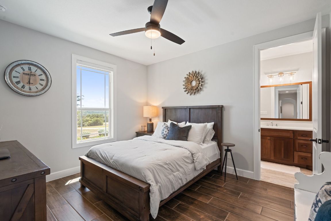 291 Southwick Ranch Road Johnson City, TX 78636 - Photo 23 of 40 Bedroom featuring wood tiled floors, a ceiling fan, and ensuite bathroom
