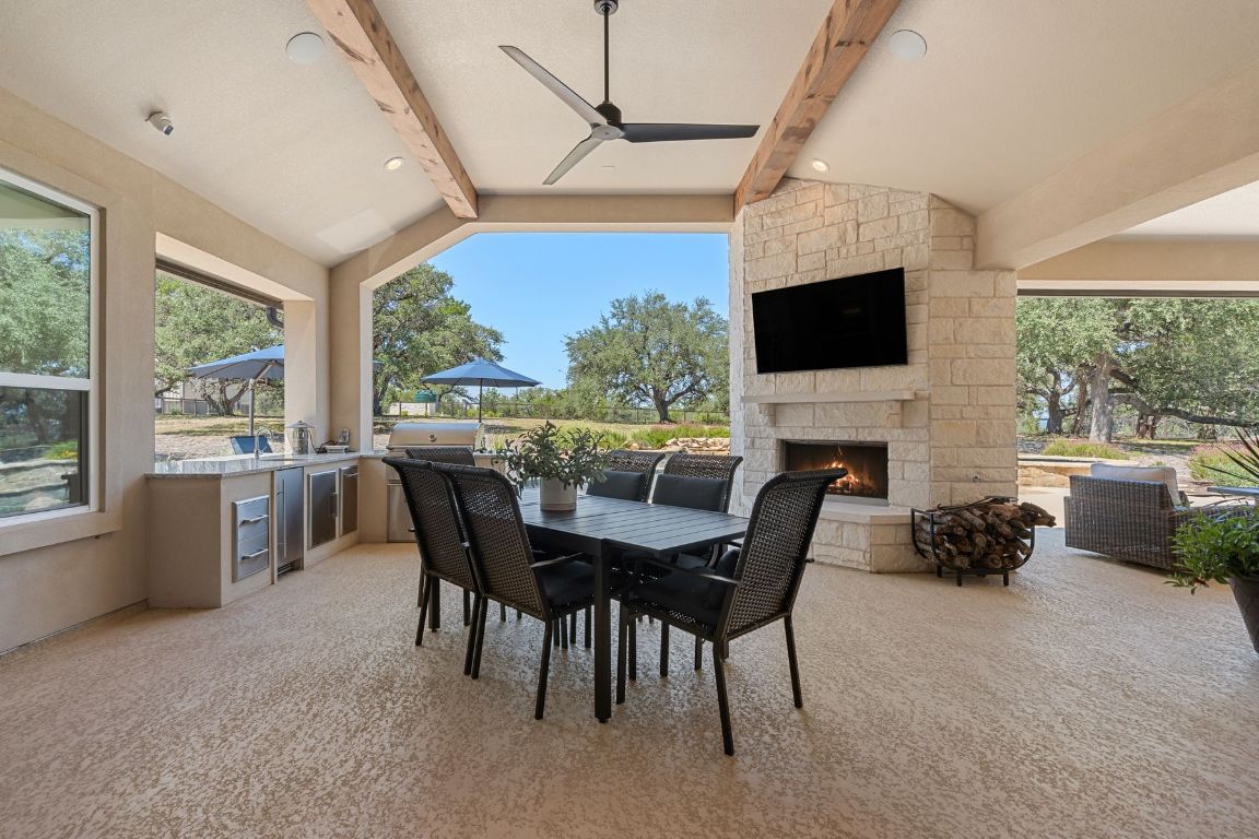 291 Southwick Ranch Road Johnson City, TX 78636 - Photo 32 of 40 View of patio / terrace with an outdoor kitchen, outdoor dining area, a ceiling fan, and an outdoor stone fireplace