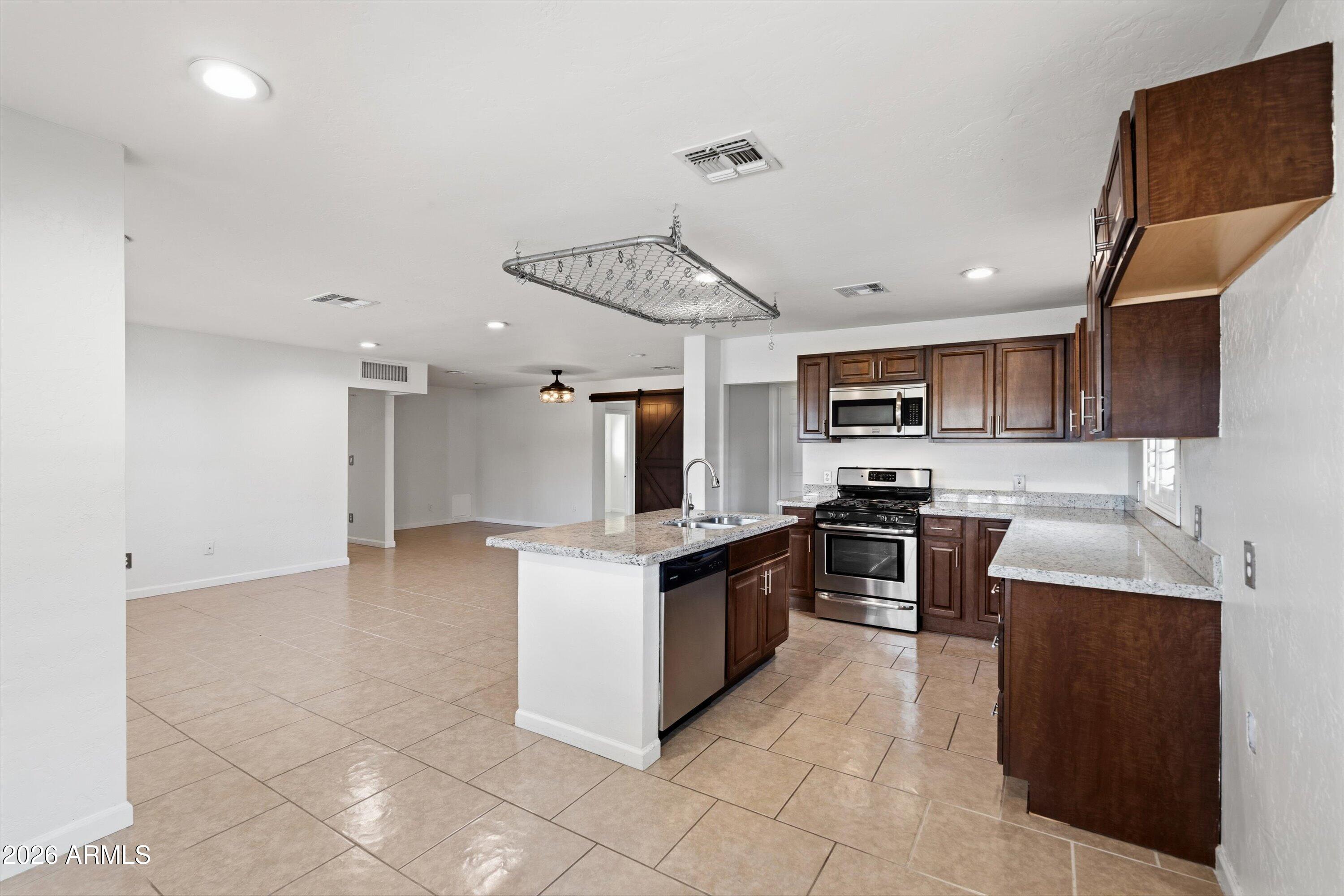 6246 North 23rd Avenue Phoenix, AZ 85015 - Photo 2 of 30 a kitchen with stainless steel appliances granite countertop a stove top oven a sink a counter top space and cabinets