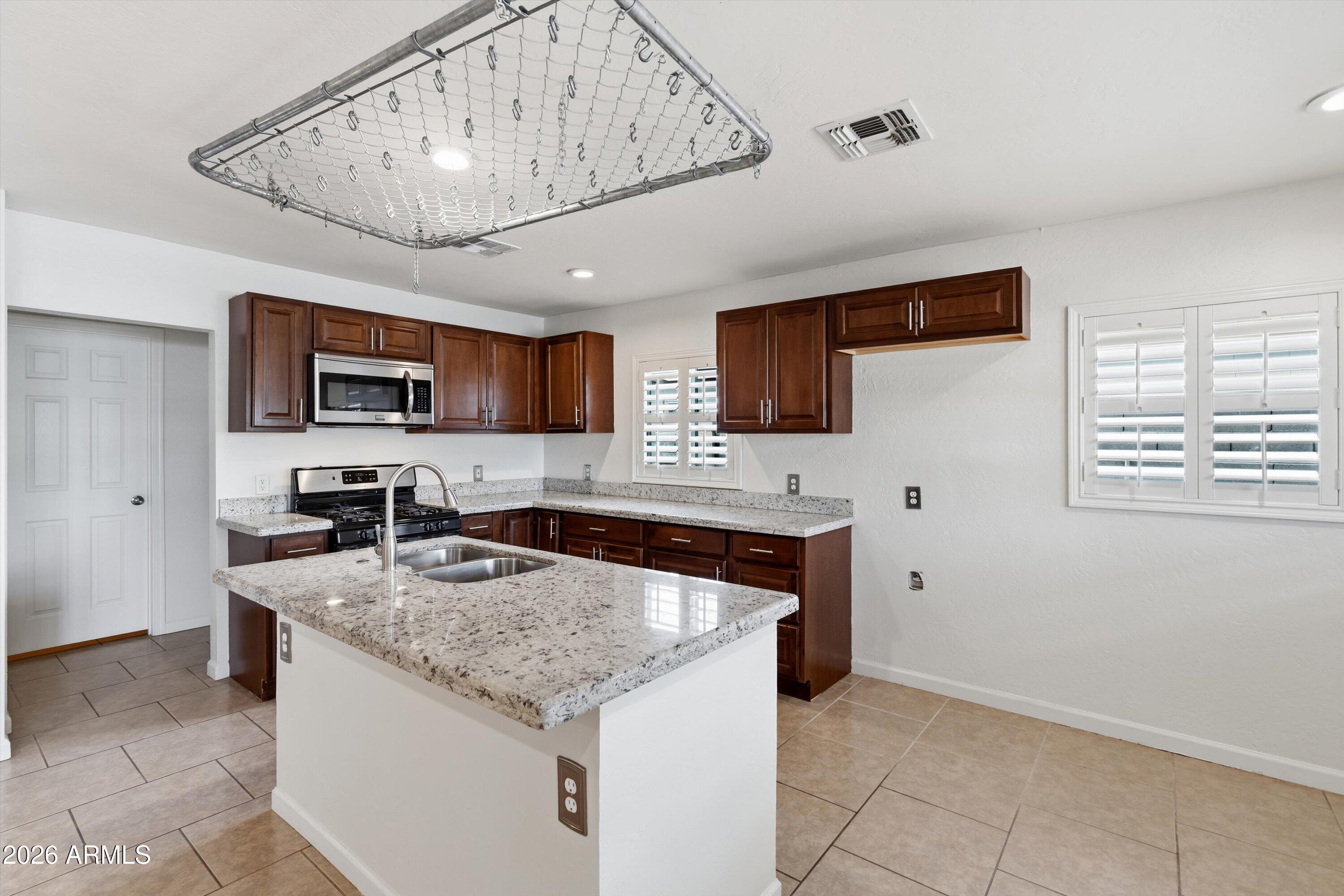 6246 North 23rd Avenue Phoenix, AZ 85015 - Photo 3 of 30 a kitchen with granite countertop a sink a counter top space cabinets and stainless steel appliances