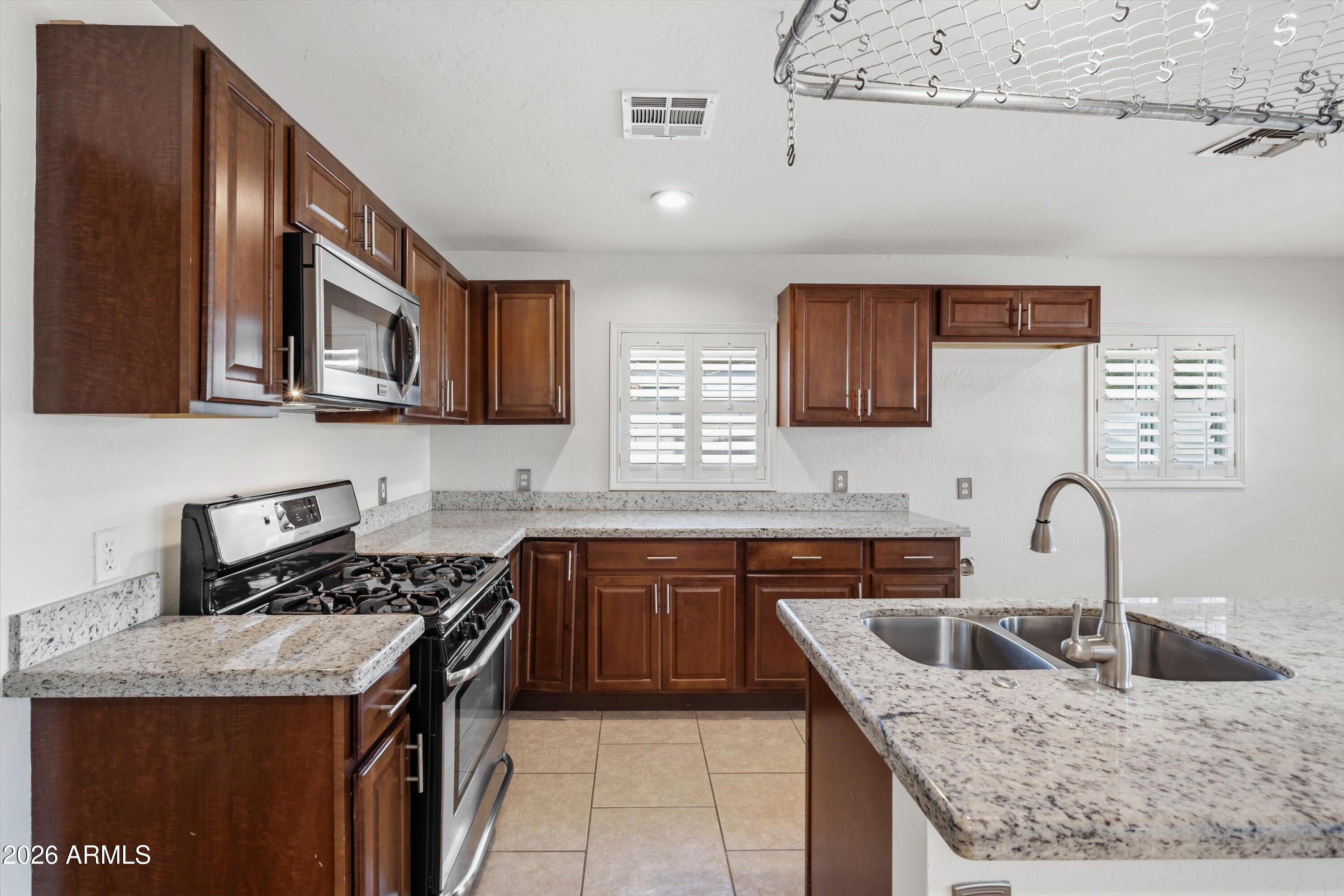 6246 North 23rd Avenue Phoenix, AZ 85015 - Photo 5 of 30 a kitchen with granite countertop stainless steel appliances a sink a stove and cabinets