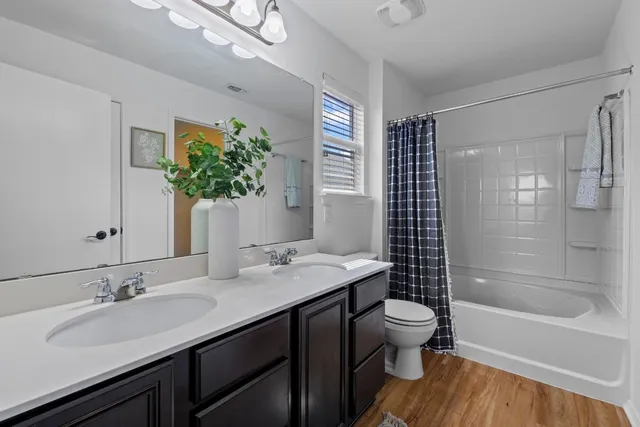 a bathroom with a granite countertop sink a toilet a mirror and shower