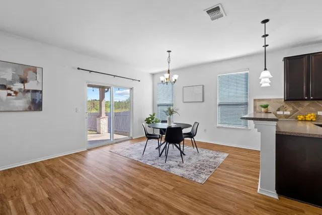 a dining room with wooden floor a chandelier a wooden table and chairs
