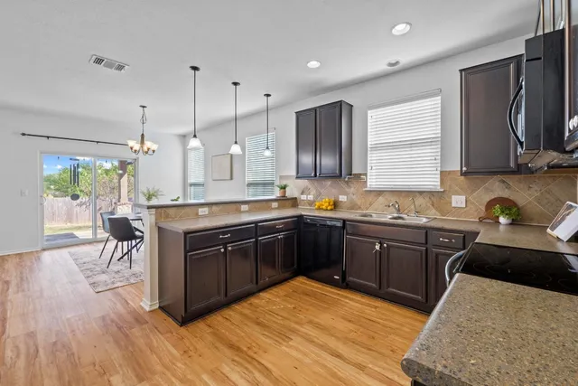 a kitchen with stainless steel appliances granite countertop a sink a stove a refrigerator cabinets and wooden floor