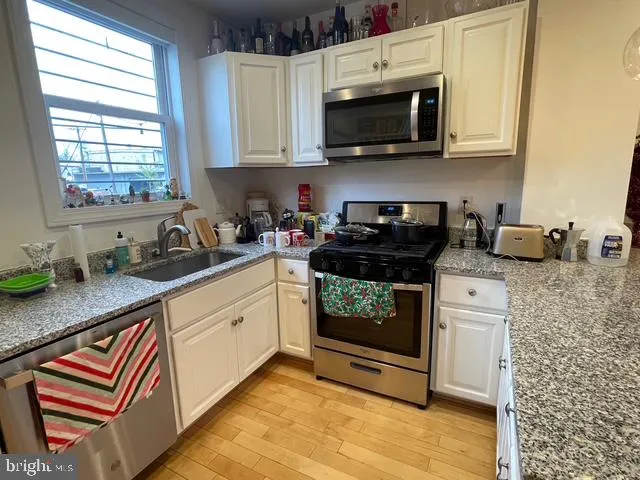 a kitchen with stainless steel appliances granite countertop a stove a sink and a microwave