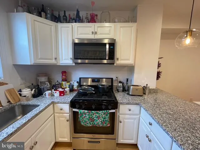 a kitchen with stainless steel appliances granite countertop a stove and a white cabinets